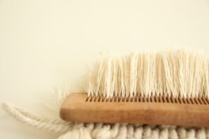 Närbild av en träborste med täta ljusa borst mot ulltextil
